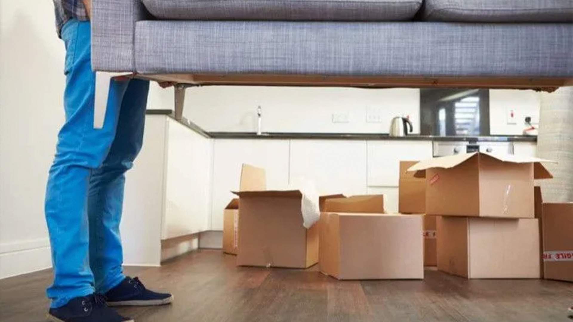 a person holding a couch under a pile of boxes